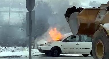 Otomobildeki yangını, iş makinesiyle toprak dökerek söndürdü