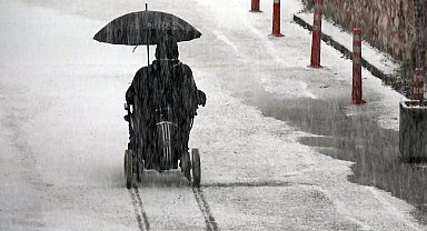 Tekerlekli sandalyesinde elindeki şemsiye ile karda ilerledi